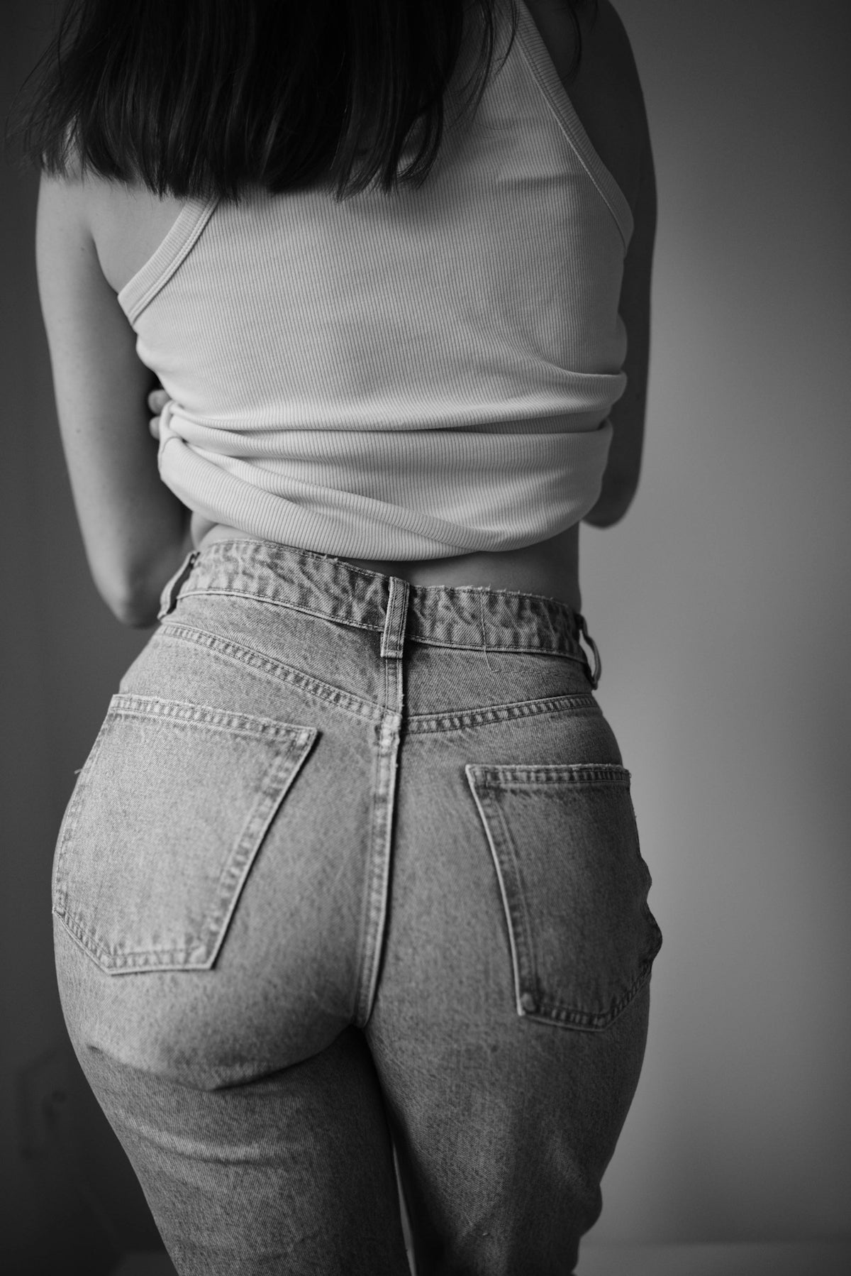 a woman in high waist jeans and a tank top