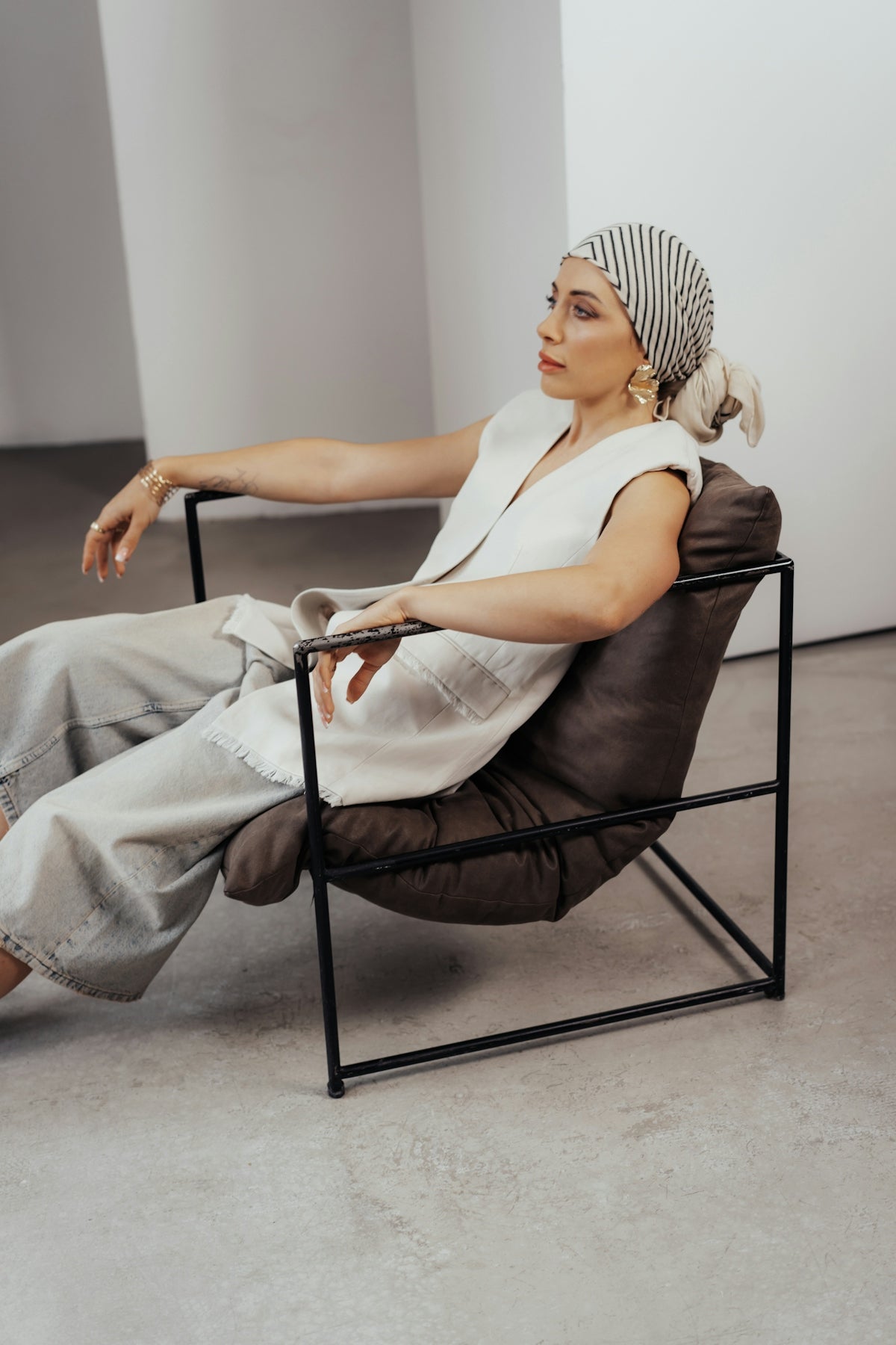 Woman in stylish outfit poses in modern chair