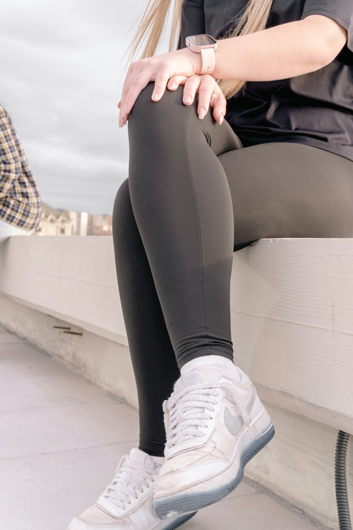 Woman in dark leggings and white sneakers sitting
