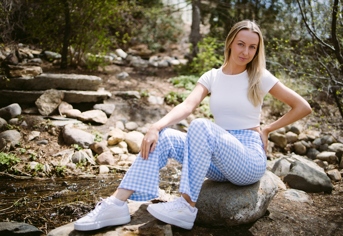 A woman sits on a rock in a wooded area.