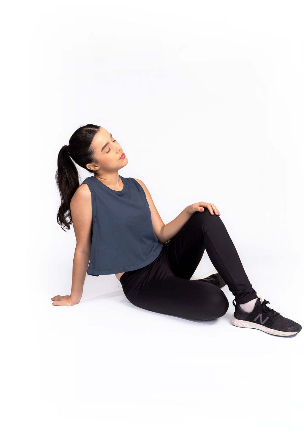 Woman in athletic wear sitting on the floor with a white background
