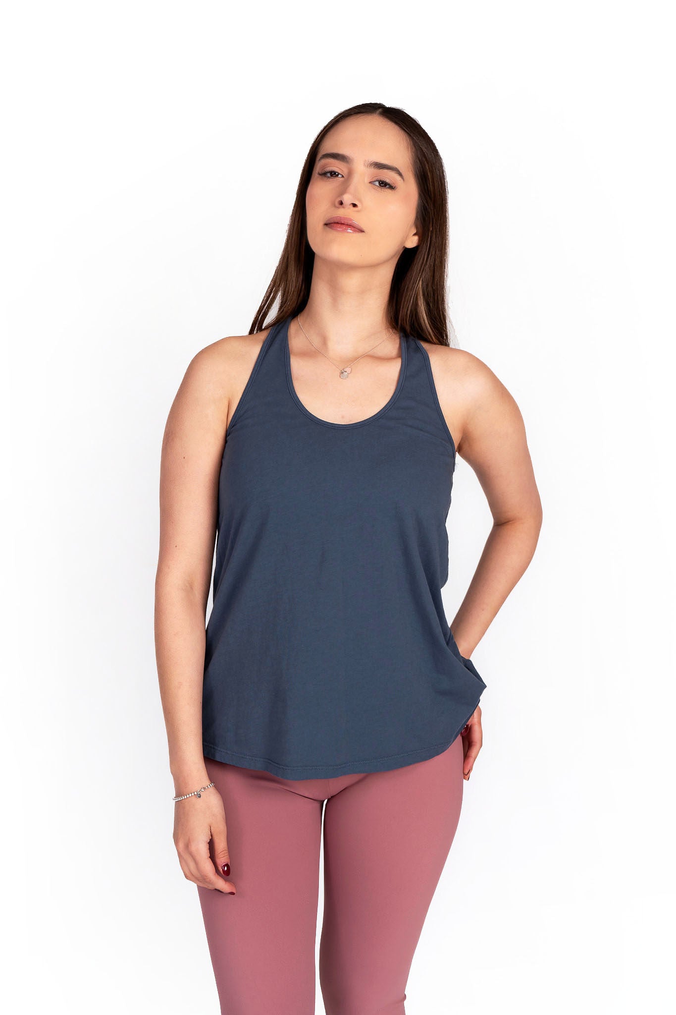 A woman wearing a purple flowy tank top with a scoop neckline and a round bottom hem, paired with a blue denim skirt.