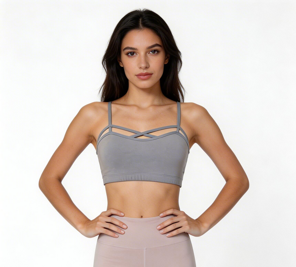 Woman wearing a gray sports bra and pink leggings on a white background